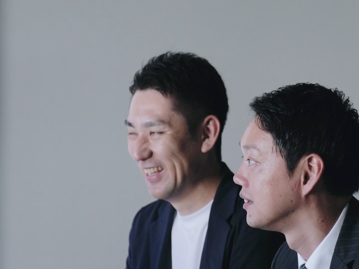 工務店の担当者と並んで笑顔で話す建築士・竹本耕平